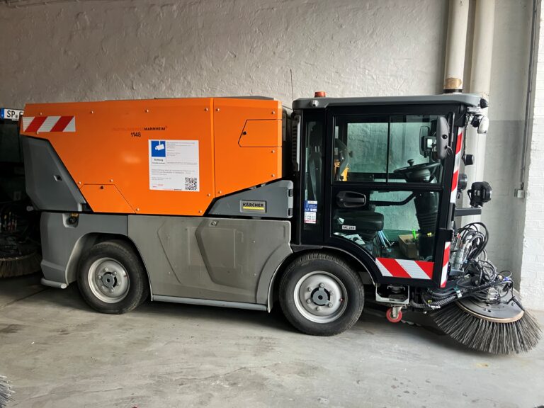 Das Bild zeigt eine Kehrmaschine mit angebrachtem Hinweisschild auf der Seite, das wesentliche Informationen zum Einsatz der Kamera enthält