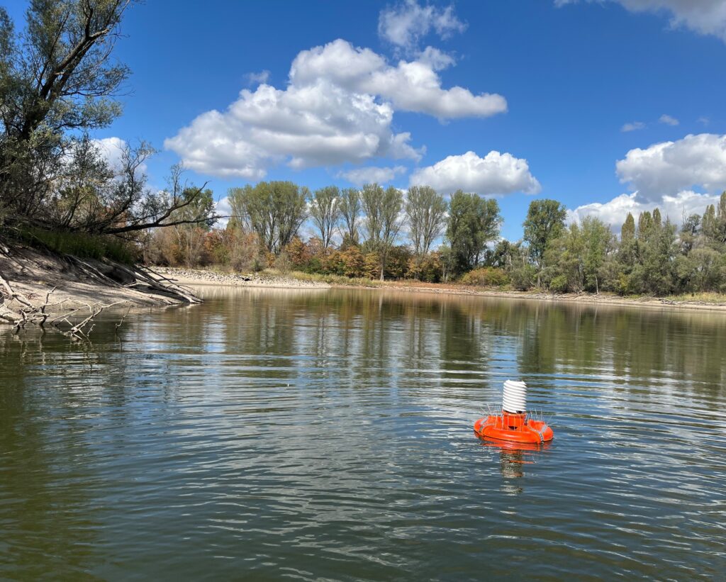 Das Bild zeigt die orangene schwimmende Klimamessstation im Wilhelmswörthweiher